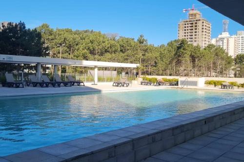 een zwembad met stoelen en een gebouw op de achtergrond bij Apartamento nuevo super full in Punta del Este