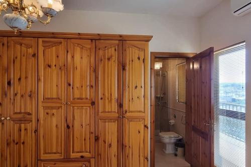 a bathroom with wooden cabinets and a toilet at Ramla Boutique Home in Marsaskala