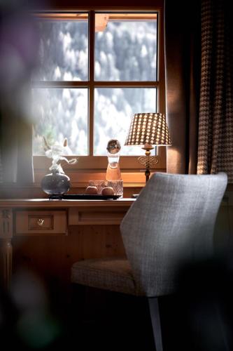 a desk with a window with a lamp and a chair at Hotel Gletscherblick in Sankt Anton am Arlberg