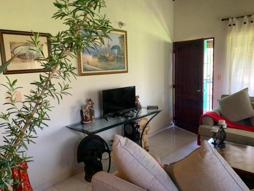 a living room with a tv and a table at Villa Fe Esperanza - Vistas al Valle de Constanza in Constanza