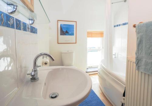 un bagno bianco con lavandino e vasca di Pontfair - Charming Cottage 10 mins walk from beach a Llangrannog