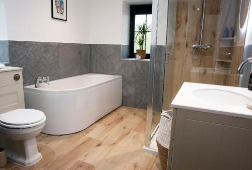 a bathroom with a tub and a toilet and a sink at The Ruin - Wood fired hot tub - Lochside - Dog friendly in Ullapool