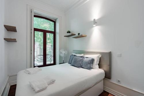 um quarto branco com uma cama e uma janela em 182 Centenario Apartment no Porto