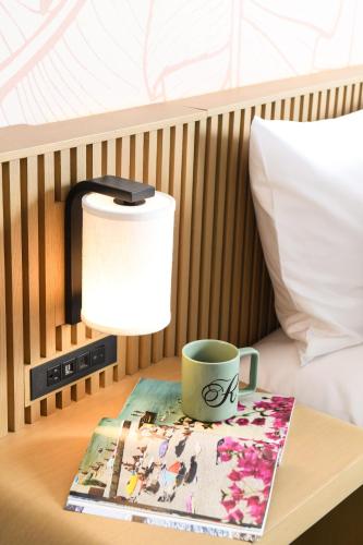 a coffee cup on a table next to a bed at The Ambassador of Waikiki, Tapestry Collection by Hilton in Honolulu