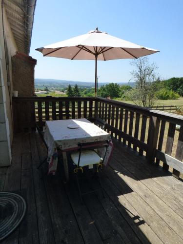 a table and an umbrella on a wooden deck at Domaine de la Borde in Puy-lʼÉvêque