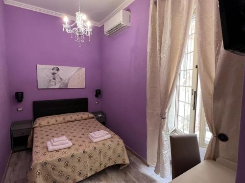 a purple bedroom with a bed with two towels on it at Guest House Biondi Cavour in Rome
