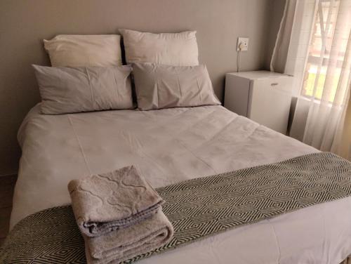 a white bed with a blanket and pillows on it at Rethapaki Guesthouse in Secunda