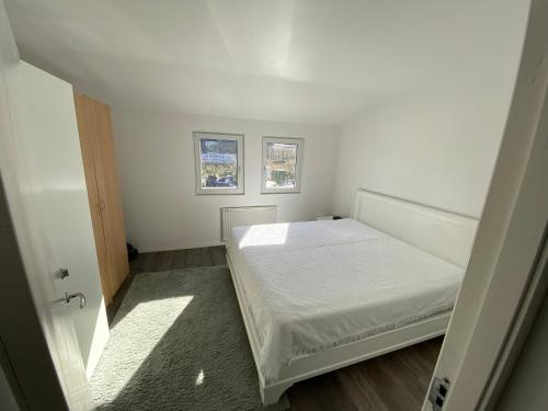 a small bedroom with a bed and two windows at Videdal apartment 2 rooms in Malmö