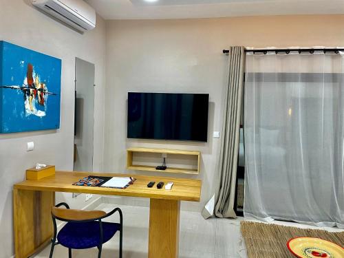 a living room with a table and a television on a wall at Le Kentia in Lomé
