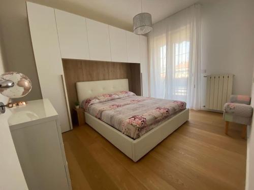 um quarto com uma cama e piso em madeira em Appartamento Luxury White em Viareggio