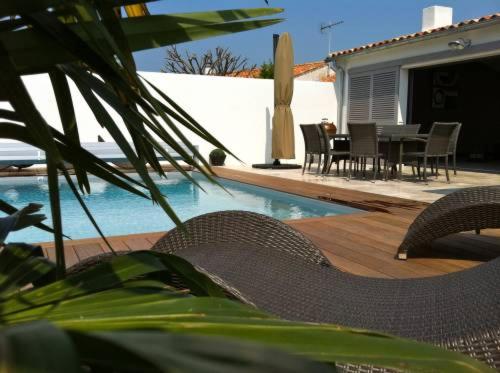 un patio avec des chaises et une table ainsi qu'une piscine dans l'établissement Les Villas de l'Embarcadère Villa La Serpent, à La Flotte