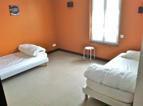 Cette chambre orange comprend 2 lits et une fenêtre. dans l'établissement Les Villas de l'Embarcadère Villa La Serpent, à La Flotte
