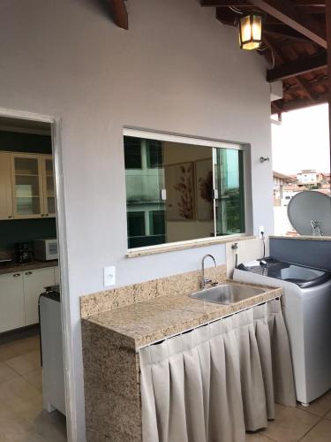 a kitchen counter with a sink and a mirror at Sinta-se em casa. in Barbacena