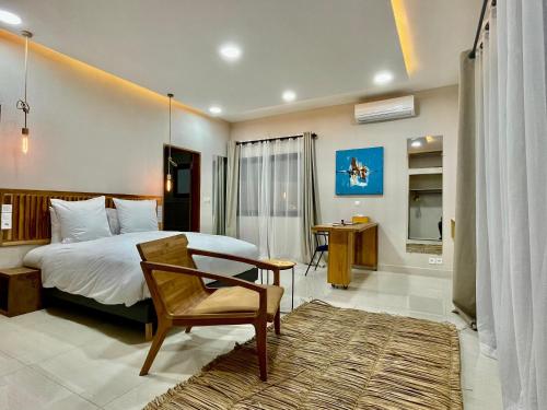 a bedroom with a bed and a chair and a desk at Le Kentia in Lomé