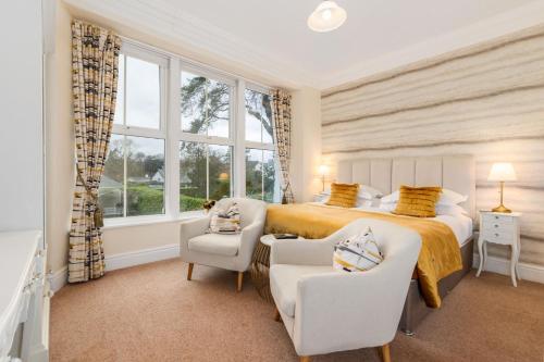 a bedroom with a bed and two chairs and a window at Wheatlands Lodge-Windermere - Award Winning - Adult Only - Car Park in Windermere