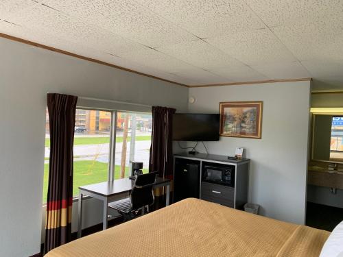 a room with a bed and a desk and a window at Pigeon Forge Parkway Inn in Pigeon Forge