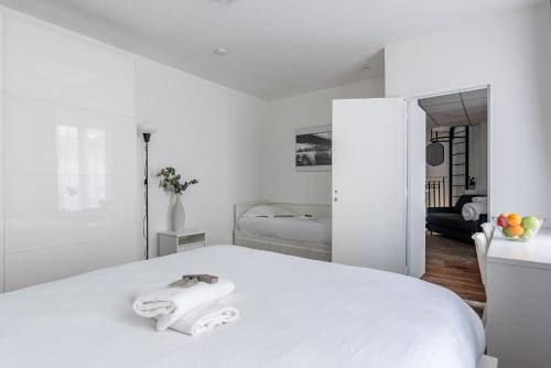 une chambre blanche avec un lit avec deux serviettes dessus dans l'établissement Loft Magenta Blue, à Paris