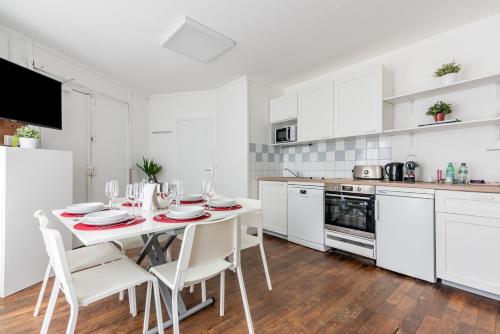 une cuisine blanche avec une table et des chaises blanches dans l'établissement Loft Magenta Blue, à Paris