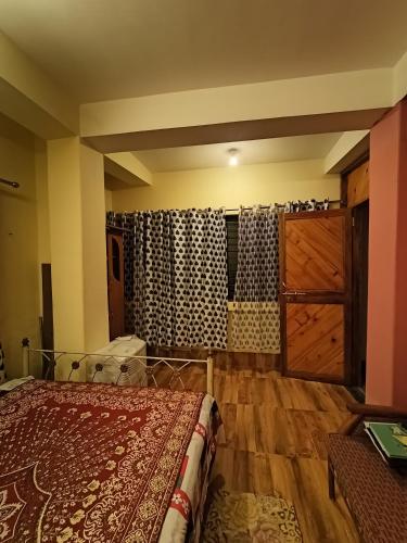 1 dormitorio con 1 cama y suelo de madera en Buddha Kuthir, en Dām Dim