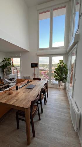 Cette grande chambre dispose d'une grande table en bois et de fenêtres. dans l'établissement Duplex de la Gare, Grande Terrasse, Jacuzzi, à Corbeil-Essonnes
