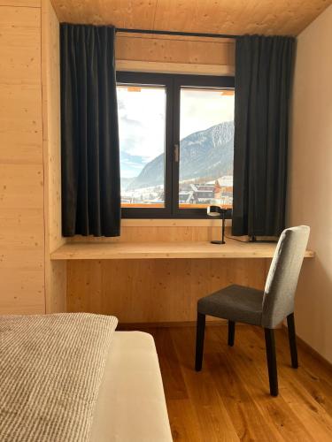 a bedroom with a window with a chair and a desk at Chalet Bergfuchs in Anterselva di Mezzo