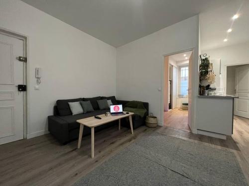 un salon avec un canapé noir et une table dans l'établissement Havre de Paix - Melun, à Melun