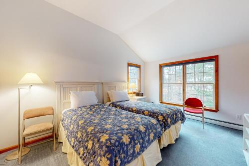 1 Schlafzimmer mit 2 Betten, einem Stuhl und einem Fenster in der Unterkunft Ski You Later in Strattonwald