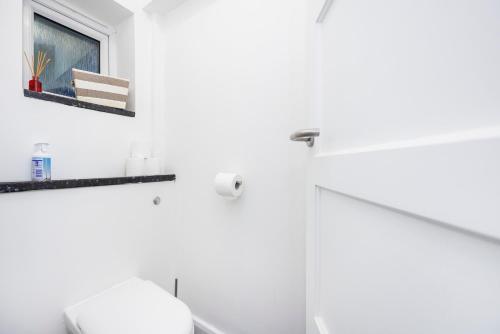 baño blanco con aseo y ventana en 3 Bedroom Flat Near Old Street, en Londres