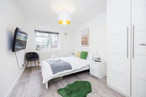 a white bedroom with a bed and a flat screen tv at 3 Bedroom Flat Near Old Street in London