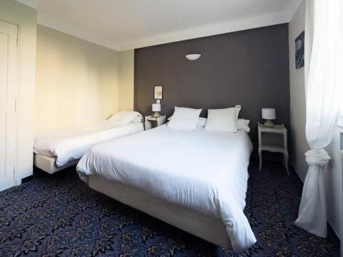 2 bedden in een hotelkamer met witte lakens en kussens bij Auberge de la Tour in Aups