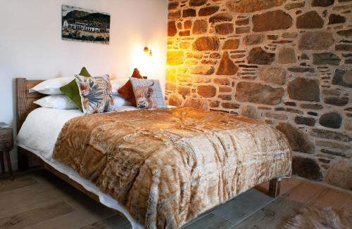 Cama en habitación con pared de piedra en The Wreck - Lochside cottage Dog Friendly, en Ullapool