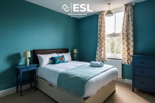 ein blaues Schlafzimmer mit einem Bett und einem Fenster in der Unterkunft 4 Bedroom House. Close to Shrewsbury Town Centre in Shrewsbury