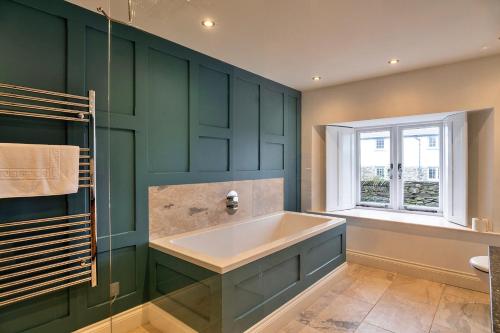 ein grünes Badezimmer mit Badewanne und Fenster in der Unterkunft Finest Retreats - Dingles Cottage in Philleigh