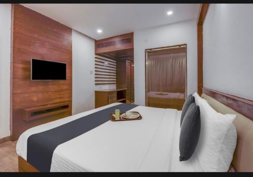 1 dormitorio con 1 cama blanca y TV en Hotel bule bell, en Patna