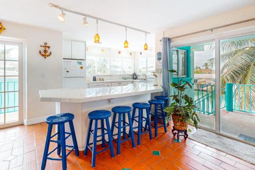 a kitchen with blue bar stools and a counter at Breezy Palms & Tropical Charm in Key Colony Beach