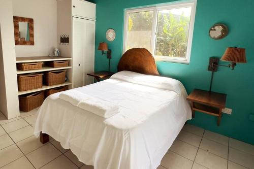 a bedroom with a white bed and a window at LaCaye - Home in Creole in Calibishie