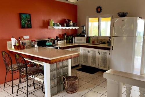 a kitchen with red walls and a white refrigerator at LaCaye - Home in Creole in Calibishie
