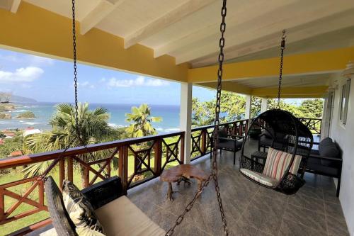a porch with a hammock and a view of the ocean at LaCaye - Home in Creole in Calibishie