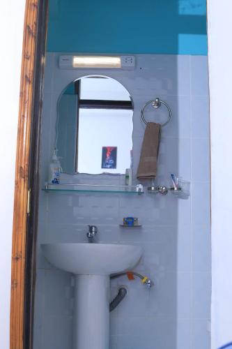 La salle de bains est pourvue d'un lavabo blanc et d'un miroir. dans l'établissement 1BR Apartment, Canopy apartments Meru near KeMU university Main Campus, à Meru