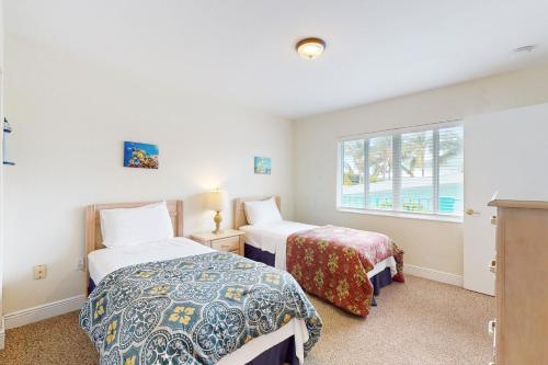 two beds in a room with a window at Breezy Palms in Key Colony Beach