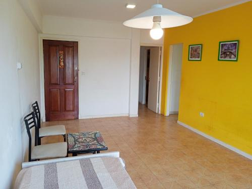 una camera con un letto e una sedia e una parete gialla di Hospedaje La Feliz a Mar del Plata
