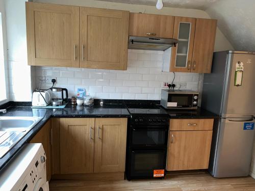 a kitchen with wooden cabinets and black counter tops at Patchway Homestay in Bristol