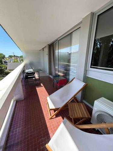un balcon avec des chaises et des tables sur un immeuble dans l'établissement Superbe appartement, terrasse, accès direct RER, à Massy