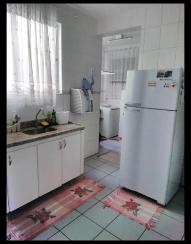 a kitchen with a white refrigerator and a sink at Quarto solteiro Praia de Camburi in Vitória