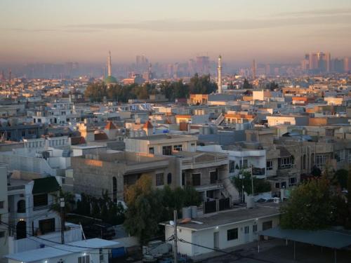 a view of a city at sunset with buildings at Vote Hotel in Erbil