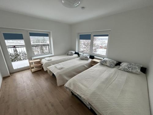 een slaapkamer met 3 bedden en 2 ramen bij Radikiai House 