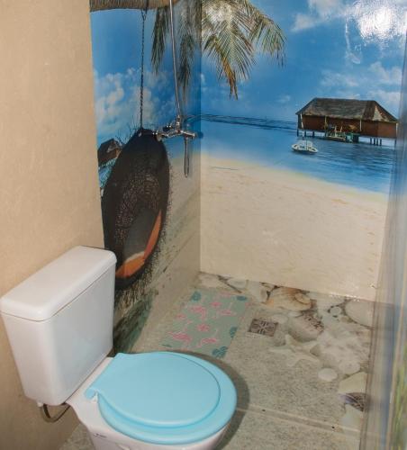a bathroom with a toilet with a painting of a beach at Cabañas Guayacán in Bialet Massé