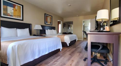 a hotel room with two beds and a desk at Quality Inn & Suites Anaheim at the Park in Anaheim