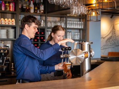 a man and a woman standing at a bar making a drink at Wadden Lodge Living in Westerland