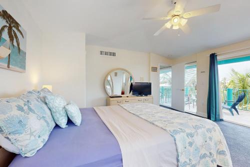 a bedroom with a bed with a ceiling fan at Tropical Charm in Key Colony Beach